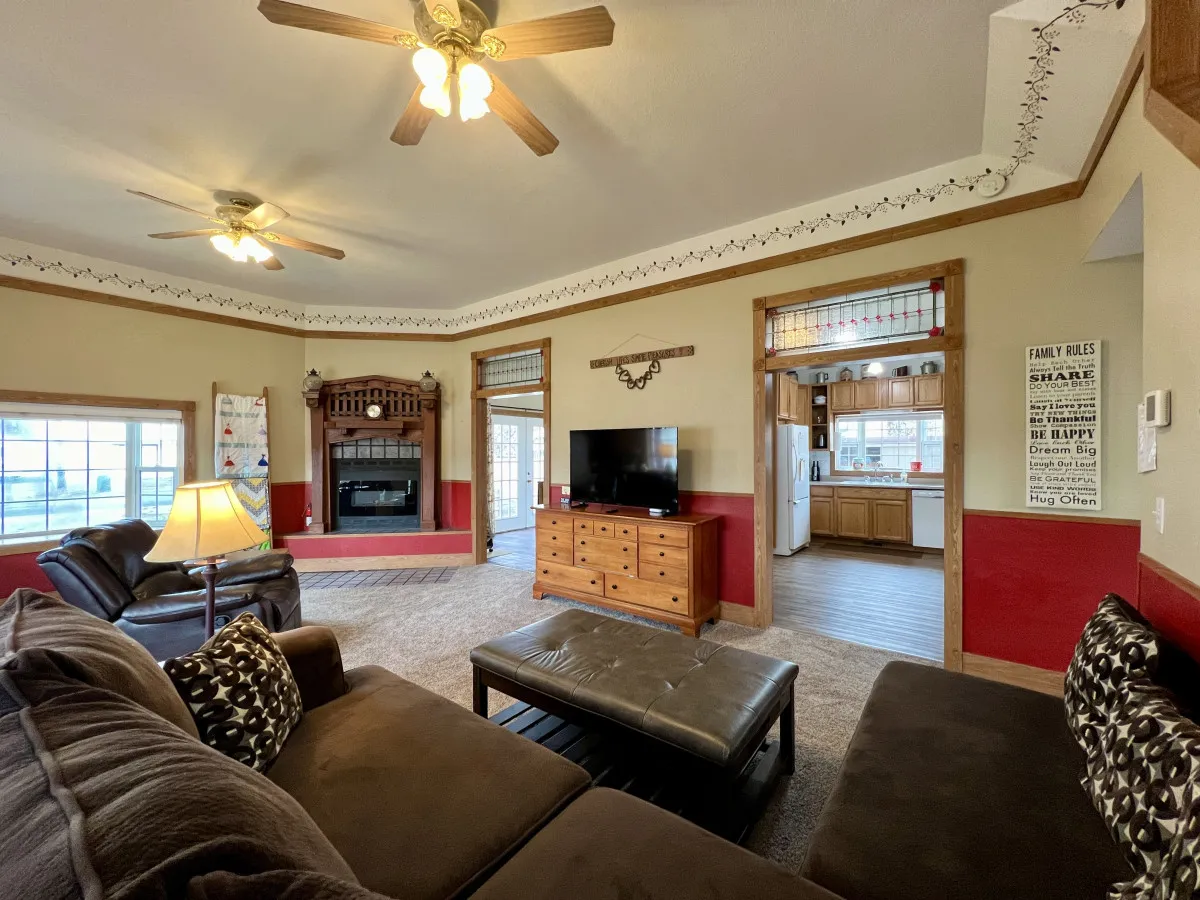 A cozy living area with a fireplace as a central focal point, a television above it, a soft sofa, and classic lamps. The scene highlights a warm and intimate setting perfect for gatherings, movie nights, and relaxation.