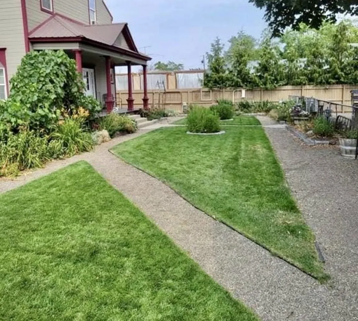 A welcoming exterior shot of Scarlet Begonia features a lush green lawn, colorful flower beds, and a charming porch. The home is seen from the outside, showcasing ample yard space and the inviting curb appeal of the property.